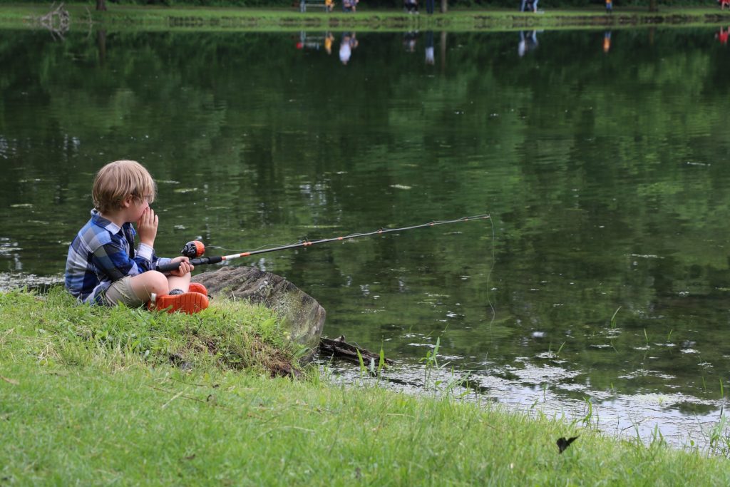 Boy with fishing pole beside lake