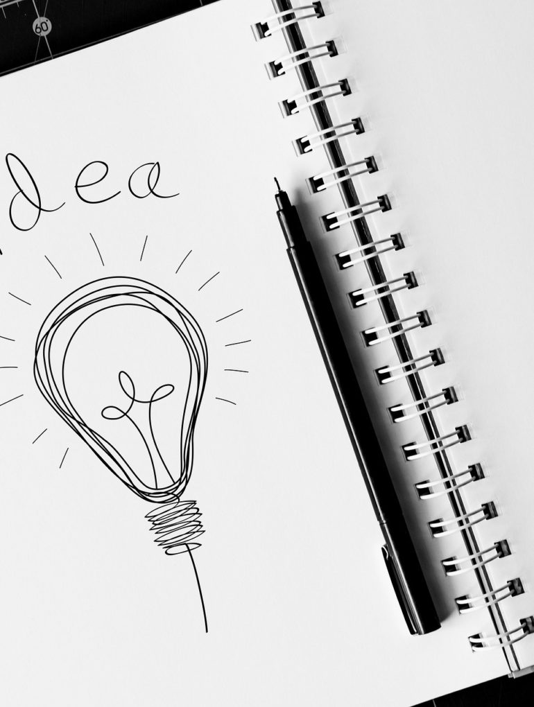 Drawing of lightbulb in notebook with the word idea written above